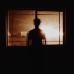 A scary image of a figure standing outside of a window